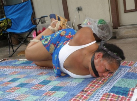 Mature ebony plumper is hogtied on a comforter while cleave gagged